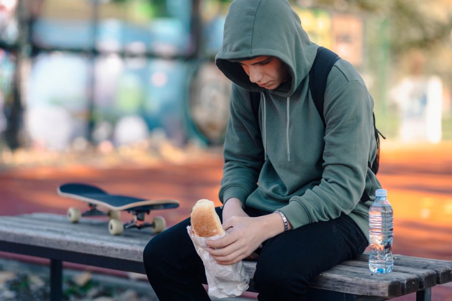 Teenager feeling sad and lonely eating lunch alone 